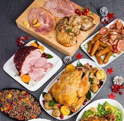 Assorted roasted meats and vegetables on a dark surface with decorative elements.