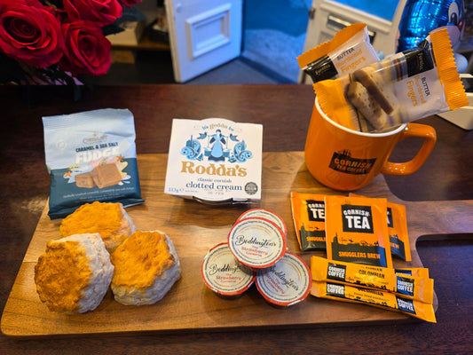 Assorted food items including biscuits, tea packages, and a mug on a wooden board.