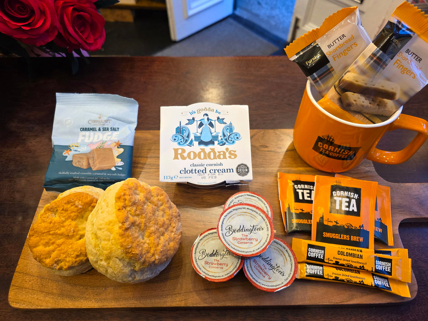Tea and biscuit set with biscuits, tea bags, and a mug on a wooden board.