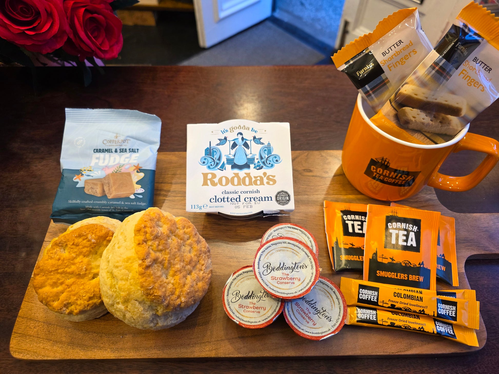 Tea and biscuit set with biscuits, tea bags, and a mug on a wooden board.