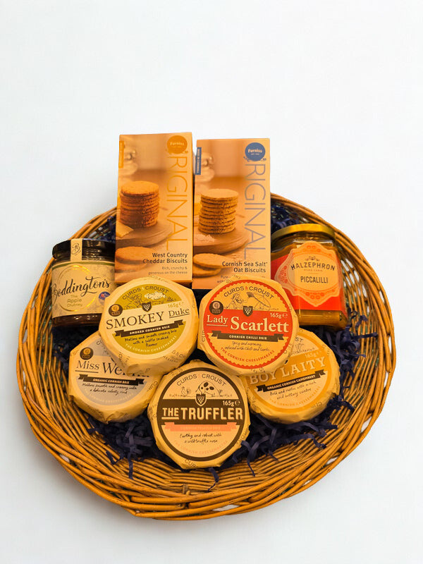 Wicker basket with various cheese and chocolate products on a white background