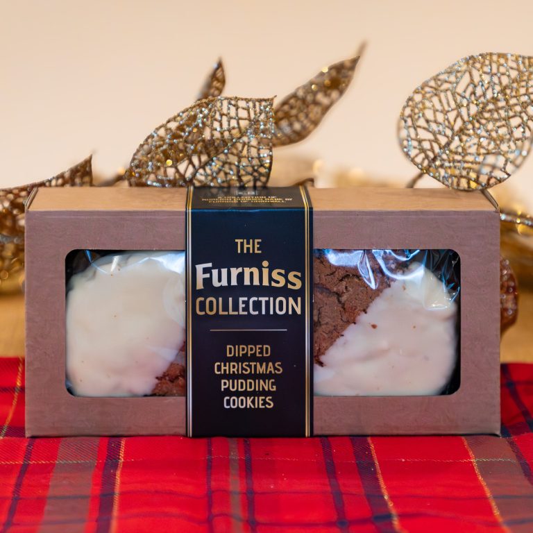 Furniss Collection dipped Christmas pudding cookies packaging on a red plaid tablecloth with decorative elements.