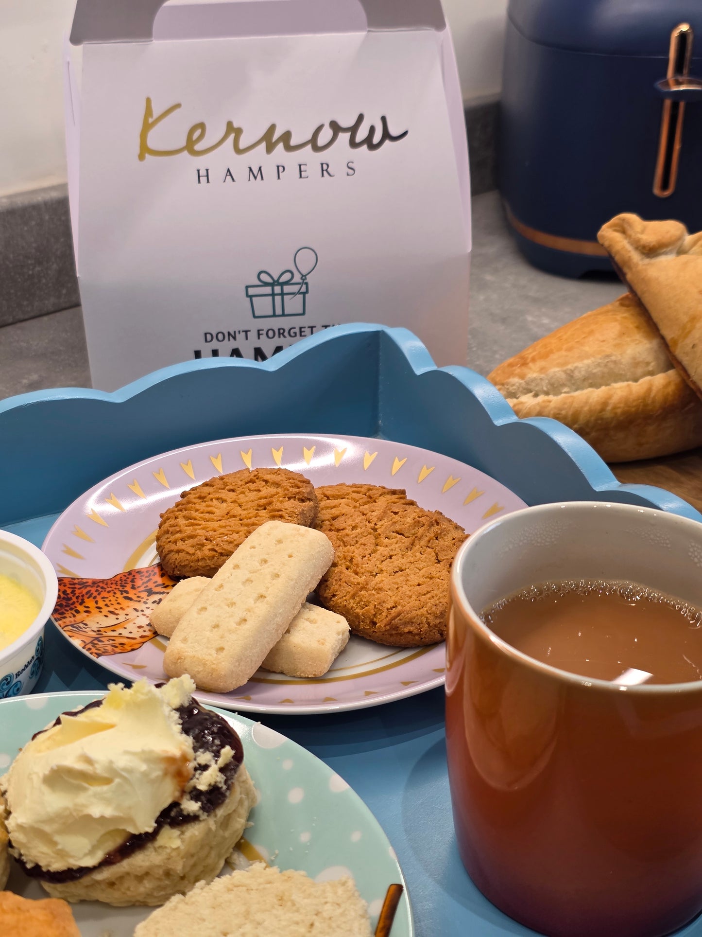 Tea time setting with furniss shortbread and ginger cookies, scones, and a Kernow Hampers bag.
