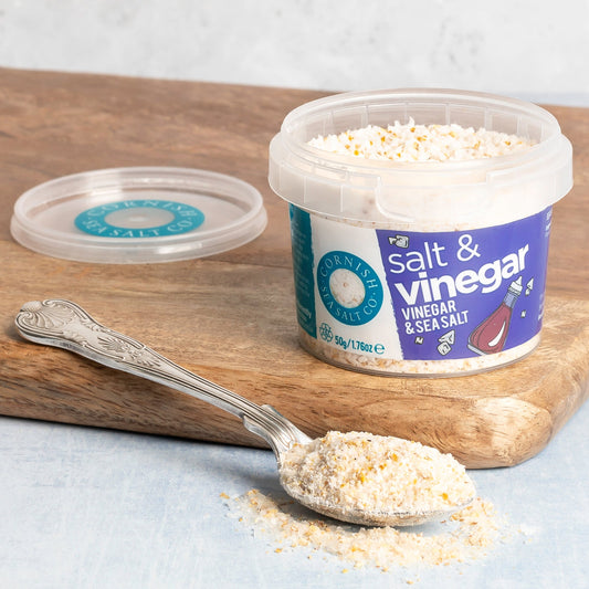 Container of salt and vinegar seasoning with a spoonful on a wooden board