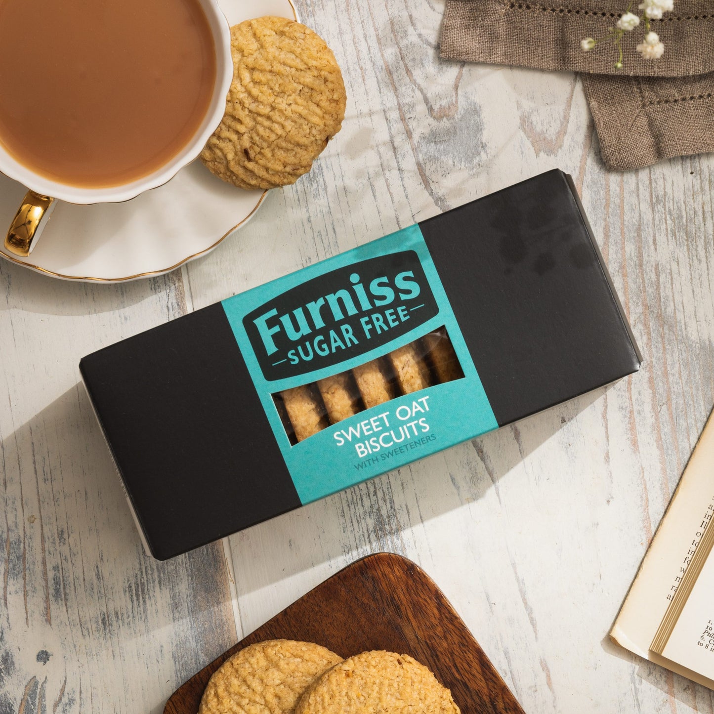 Box of Furniss Sugar Free Sweet Oat Biscuits on a wooden surface with a cup of tea and cookies.